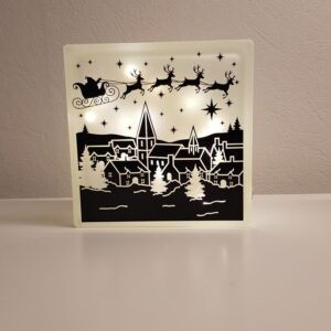 Lyssten med julemotiv. Julemandens kane over landsby